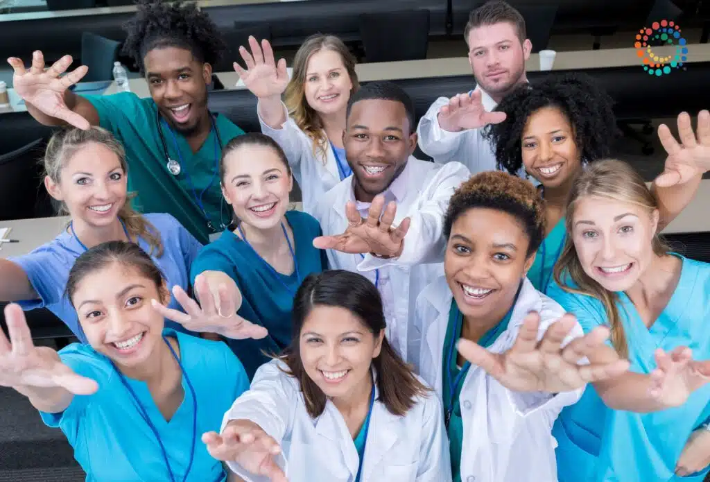 Group of diverse, smiling clinicians reaching towards the camera