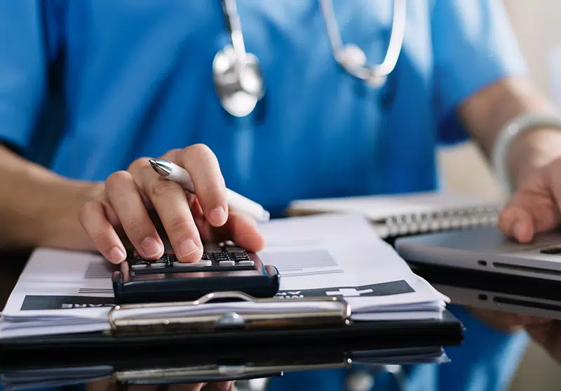 Close up of doctor's hand as he uses a calculator